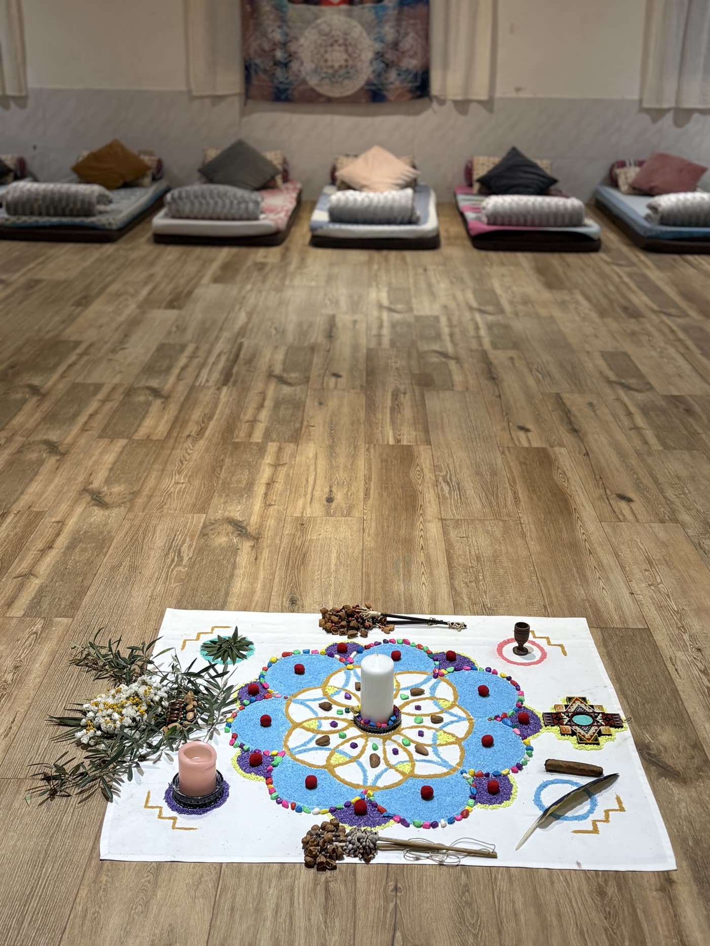 Sala de ceremonia con colchones, cojines y altar de flores en el centro